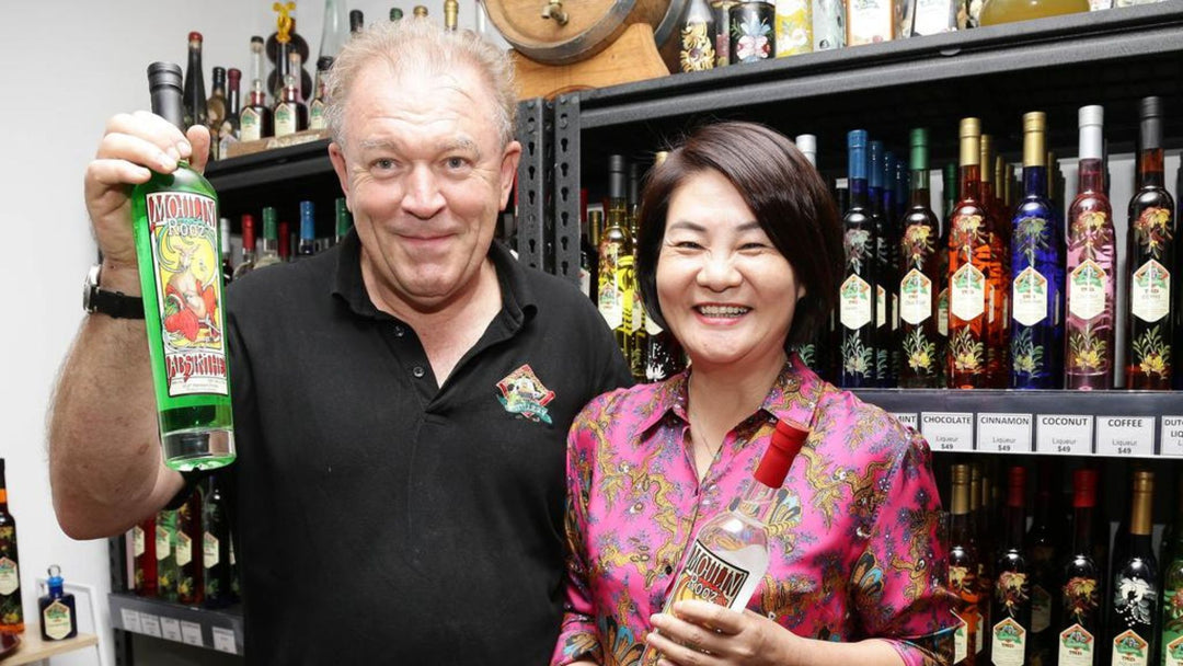 Gordon Chalmers & Shumei Hou holding bottles in front of our Tamborine Mountain Distillery shop