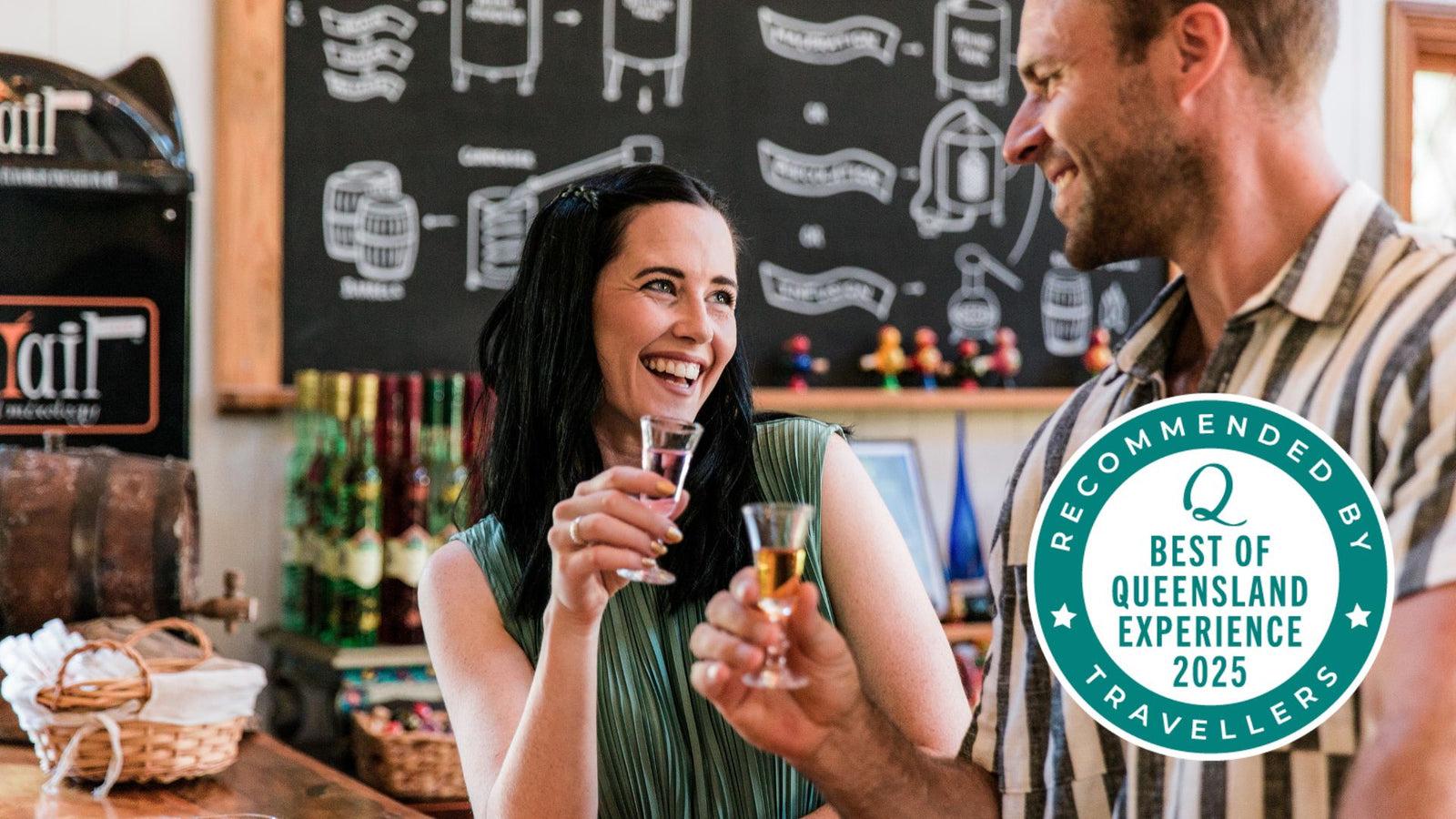 Two people enjoying drinks at Tamborine Mountain Distillery tasting room with a 'Recommended by Queensland Experience Travellers' badge.