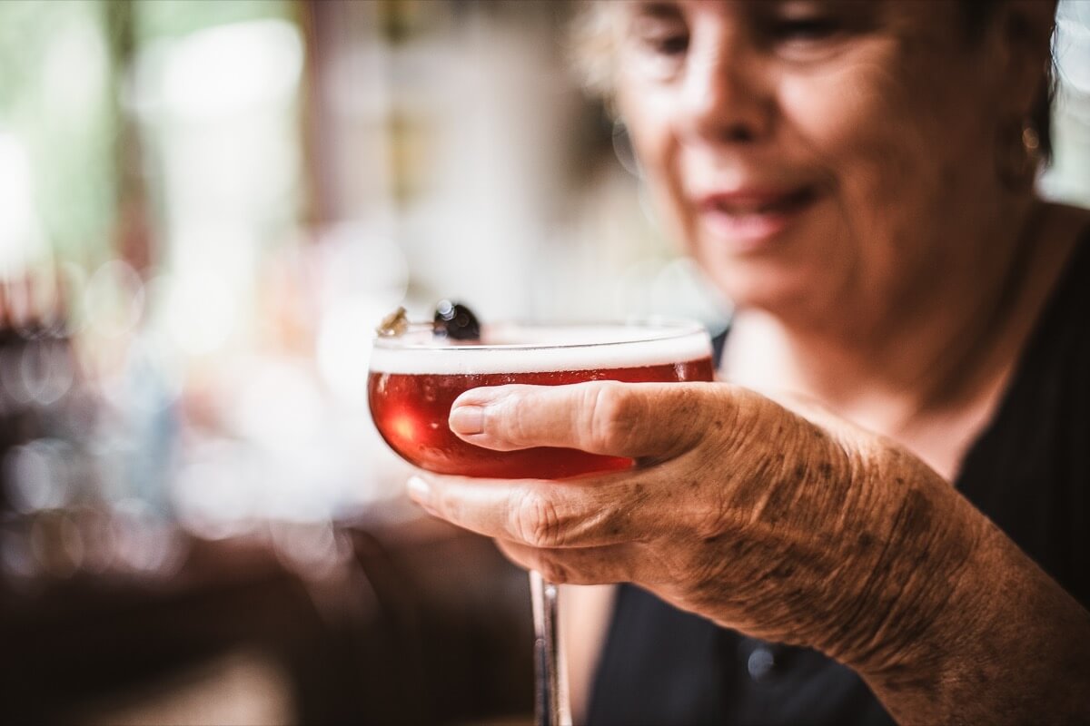 smiling elderly gentleman raising a glass to toast