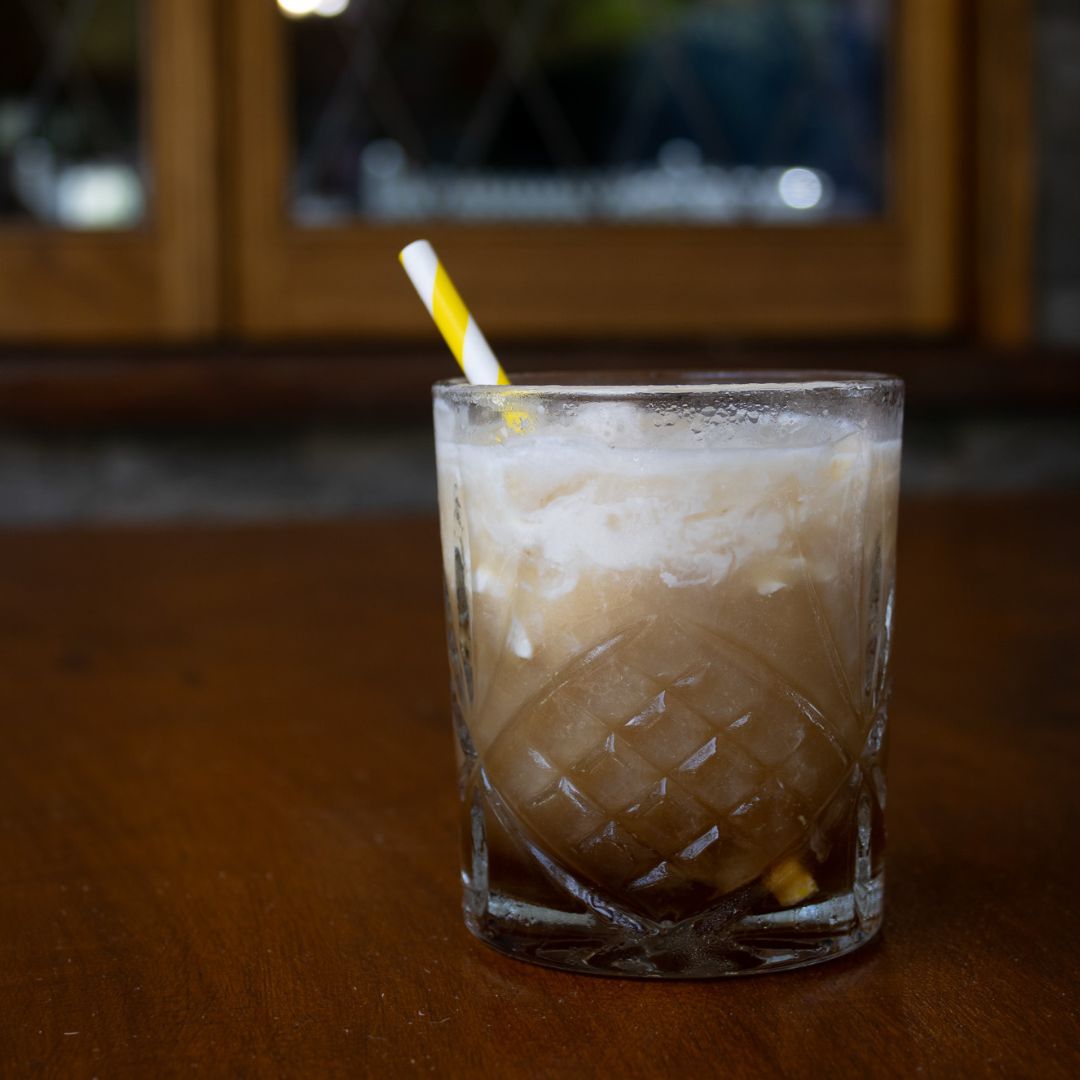 Tamborine White Russian with Neutral Vodka, Butter Whiskey, Coffee Liqueur, and cream, served layered over ice in a whiskey glass.