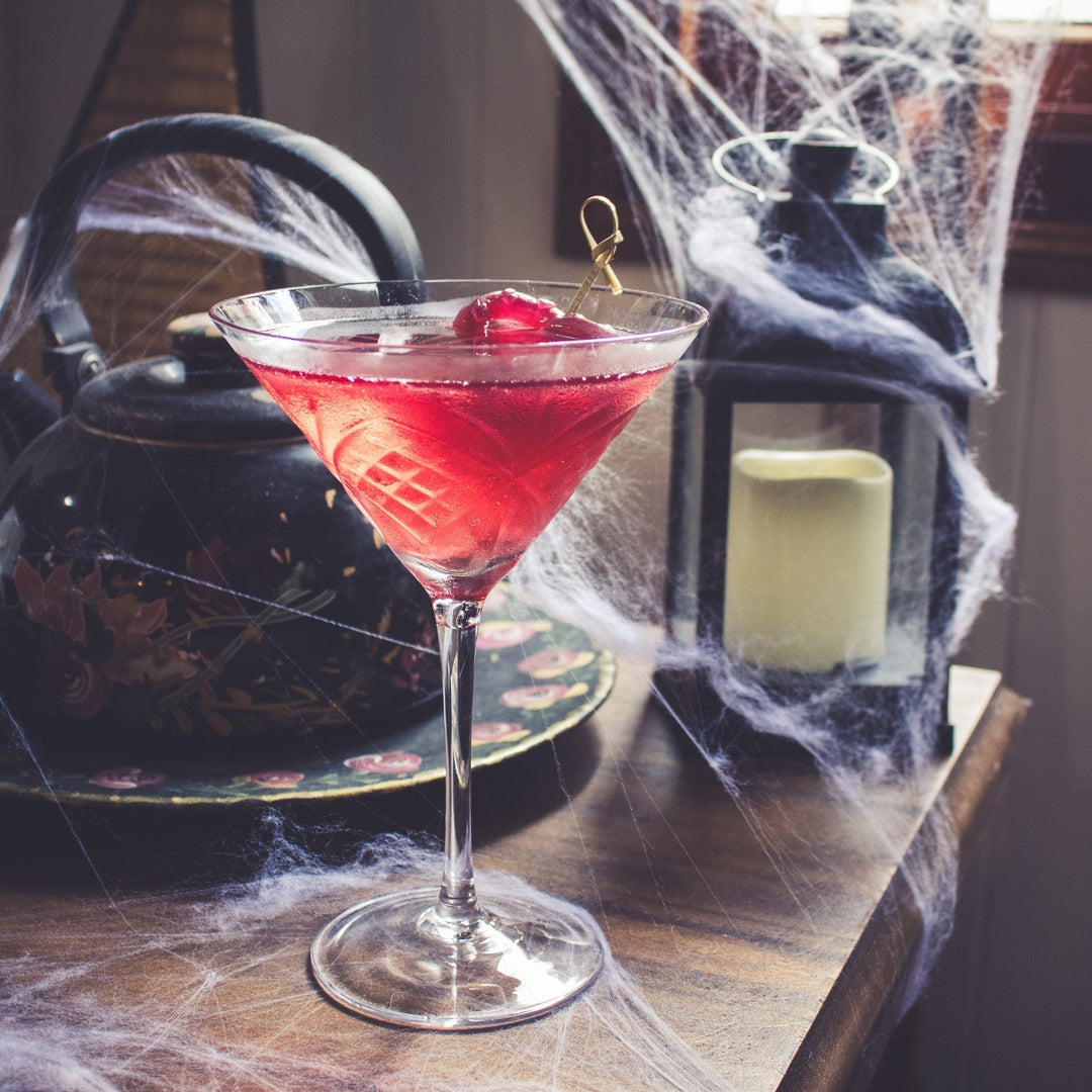 Spooky Vampire’s Kiss Halloween cocktail with Wild Citrus Vodka, Wild Forest Plum & Strawberry Liqueur, cranberry juice, and candy garnish.