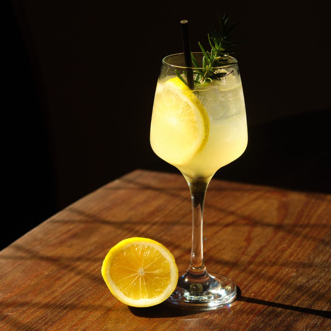 Refreshing Limoncello Spritz with TMD Limoncello, Prosecco, and soda water, served over ice in a wine glass with rosemary and lemon garnish.