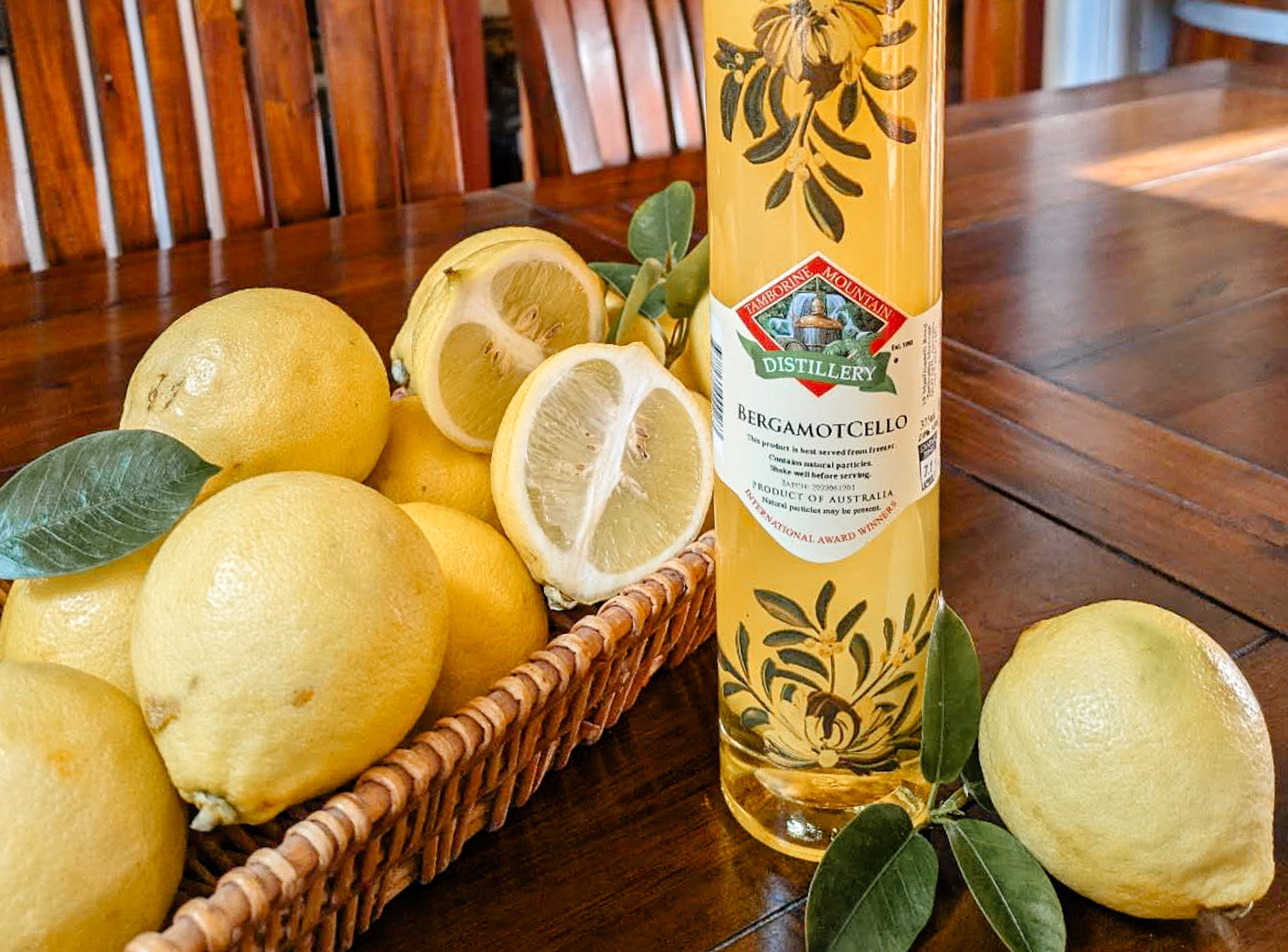 Bottle of Tamborine Mountain Distillery BergamotCello with fresh bergamot fruits displayed on a rustic wooden table
