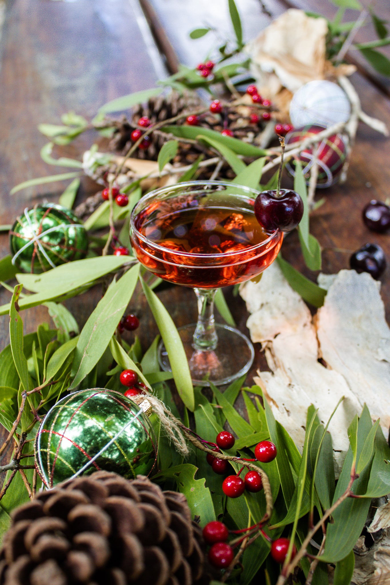 Christmas Cocktail in a glass with berries and greenery on a rustic surface