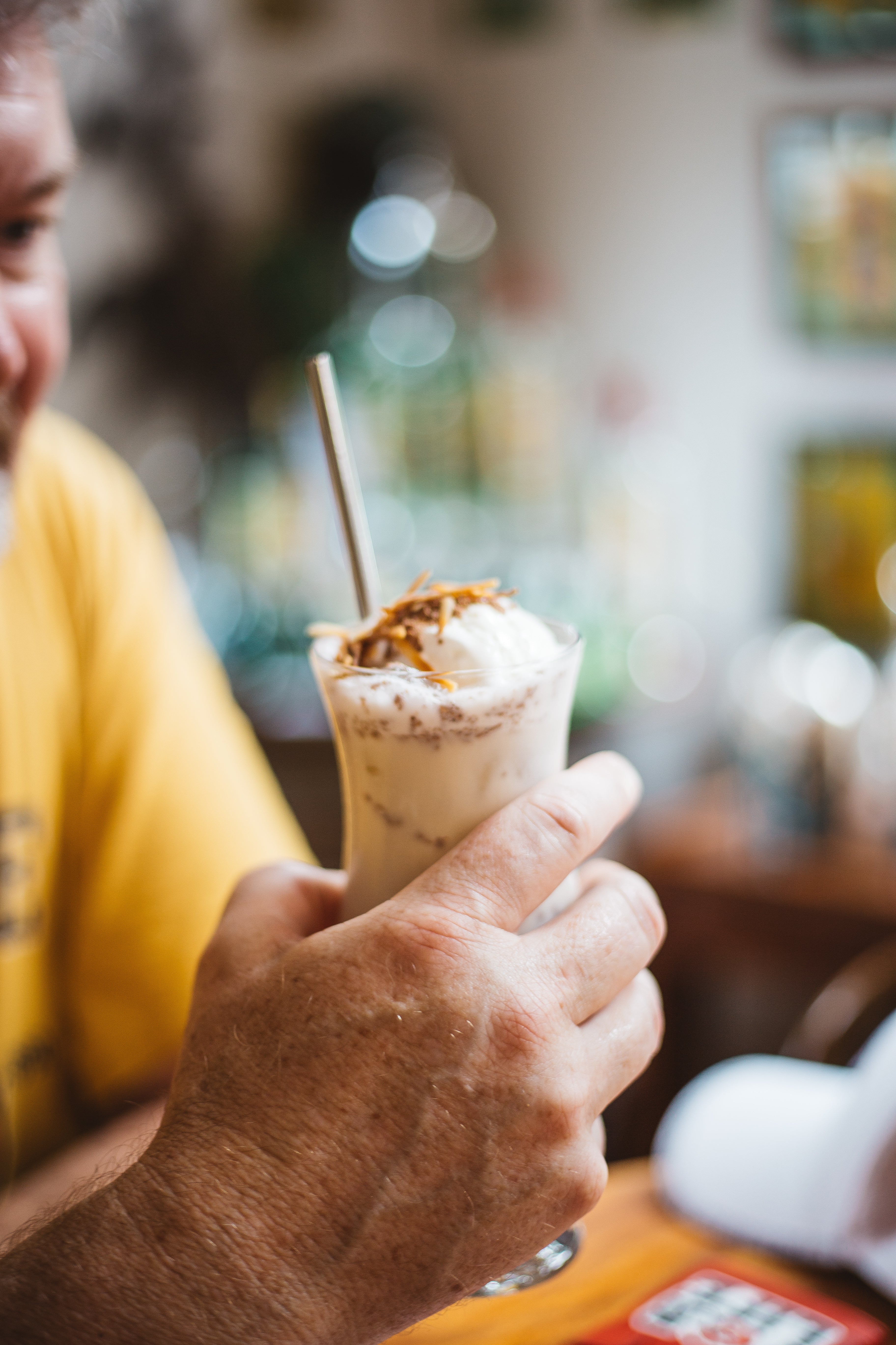 Close-up of a man’s hand holding a beautifully crafted Tamborine Mountain Distillery cocktail with garnish.