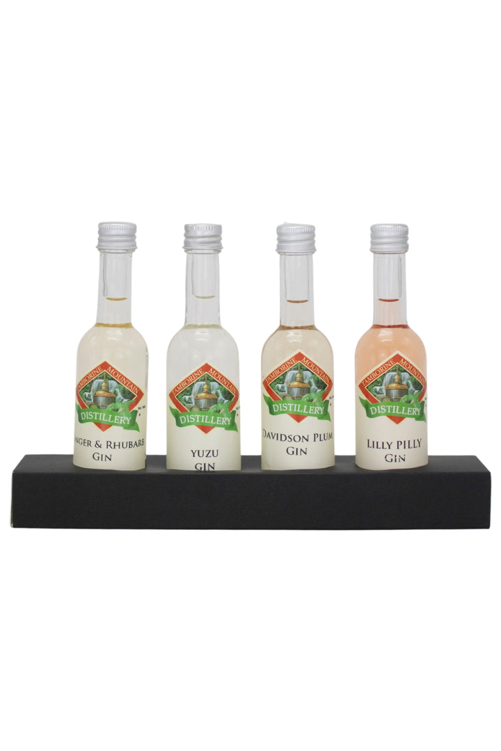 Four miniature gin bottles on a black stand with a white background